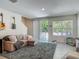 Open-concept living room features gray rug, plush sofa, TV, balcony access, and lots of light at 67 Bella Oaks Dr, Port Orange, FL 32129
