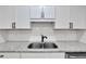 Close up of a kitchen sink featuring granite countertops, white cabinets, and a stainless steel sink at 1616 Huntington St, Lakeland, FL 33801