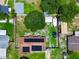 Backyard aerial view with the home, a boat, sheds, mature trees, and lush green lawn at 1841 Talmadge St, Deland, FL 32724