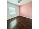 An Empty bedroom showcasing wood floors, a window, and pink accent wall at 2864 Running Brook Cir, Kissimmee, FL 34744