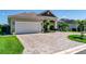 Charming single-Gathering home featuring a brick paved driveway, two car garage, and tropical landscaping at 3249 Pearly Dr, Lakeland, FL 33812