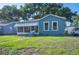 Charming blue cottage-style home with a quaint front porch, awning, lush lawn, and mature trees at 549 Palencia Pl, Lakeland, FL 33803