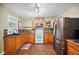 Well-lit kitchen features wood cabinets, tile backsplash, stainless steel refrigerator, and a black sink and faucet at 549 Palencia Pl, Lakeland, FL 33803