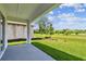 Covered patio overlooks the lush green lawn and serene landscaping of the home's backyard at 6068 Sacred Oak Ave, Mount Dora, FL 32757