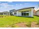 View of a large grassy backyard featuring a covered patio and lush landscaping for outdoor enjoyment at 6068 Sacred Oak Ave, Mount Dora, FL 32757