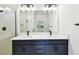 Modern bathroom featuring double sinks, quartz counters, dark vanity and a tiled shower at 6068 Sacred Oak Ave, Mount Dora, FL 32757