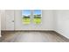 Cozy bedroom with wood-look floors, two windows with backyard view, and a white door at 6068 Sacred Oak Ave, Mount Dora, FL 32757