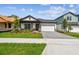 Inviting home exterior featuring a landscaped front yard, red door, gray driveway pavers, and a two-car garage at 6068 Sacred Oak Ave, Mount Dora, FL 32757