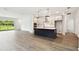Open kitchen with stainless steel appliances, white cabinets, dark island and wood-look floors at 6068 Sacred Oak Ave, Mount Dora, FL 32757