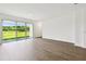 Bright, open-concept living room featuring wood-look floors and large sliding glass doors to backyard at 6068 Sacred Oak Ave, Mount Dora, FL 32757