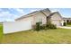 Side view of a beige home showing manicured lawn, white fence, and partial view of the garage at 887 Galloway St, Lake Alfred, FL 33850