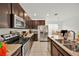 Kitchen with dark wood cabinets, stainless steel appliances, granite countertops and tile floors at 890 Marisa Ln, Kissimmee, FL 34744