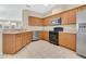 Open kitchen with wood cabinets, stainless steel appliances, and a convenient breakfast bar at 12975 Calderdale Ave, Windermere, FL 34786