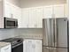 Detailed view of kitchen featuring stainless steel appliances and white subway tile backsplash at 1737 N Lakewood Ave, Ocoee, FL 34761