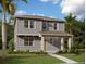 Charming two-story home with gray siding, a cozy front porch, and lush landscaping on a sunny day at 2359 Zuni Road, St Cloud, FL 34771