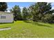 A spacious backyard with lush green grass, mature trees, and a partial view of the home's exterior at 5008 Vanguard St, Orlando, FL 32819