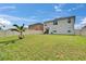 Backyard featuring a grass lawn, palm tree, and a beige house at 623 Grove St, Winter Haven, FL 33881