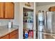 Pantry with shelving stocked with various items, next to a stainless steel refrigerator and wood-finished cabinets at 623 Grove St, Winter Haven, FL 33881