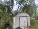 Exterior metal shed located in the backyard with overgrown vegetation around it at 7175 Se 123Rd Pl, Belleview, FL 34420