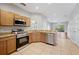 Bright kitchen with stainless steel appliances, tile flooring, granite countertops, and natural wood cabinets at 4034 Winding Vine Dr, Lakeland, FL 33812