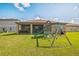 Spacious backyard featuring a playset, green lawn, and screened lanai at 4710 Osprey Way, Winter Haven, FL 33881