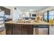 Granite kitchen island with sink, stainless steel dishwasher and dark wood cabinets at 4710 Osprey Way, Winter Haven, FL 33881