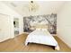 Bright bedroom with a decorative chandelier, natural light, wood floors, and a nature-themed accent wall at 132 Canary Island Cir, Davenport, FL 33837