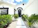 Welcoming entryway with a black front door, white stone pathway, and lush tropical landscaping at 132 Canary Island Cir, Davenport, FL 33837