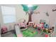 Playroom with pink walls, decorative tree mural, and toddler toys at 1704 Felicity Ln, Kissimmee, FL 34744