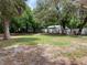Large backyard with a mix of green grass and dirt, and a view of trees at 309 Sunnyside Ln, Debary, FL 32713