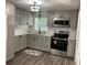 Well-lit kitchen with modern cabinets, stainless steel appliances, quartz countertops, and wood-look flooring at 309 Sunnyside Ln, Debary, FL 32713
