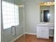 Bathroom featuring glass block window, a single sink, white cabinetry, and laminate floors at 3629 Welsh Way, Lakeland, FL 33813