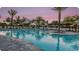 Resort style swimming pool with umbrellas and palm trees at sunset at 852 Arbor Green Trl, St Cloud, FL 34771
