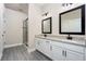 Bathroom with double sinks, granite counters, black fixtures, and a glass-enclosed shower at 7728 Somersworth Dr, Kissimmee, FL 34747