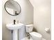 Stylish half bath with pedestal sink, round mirror and modern fixtures at 319 Ravenshill Way, Deland, FL 32724