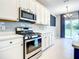 Stylish kitchen featuring white cabinets, stainless steel appliances, and tile backsplash at 319 Ravenshill Way, Deland, FL 32724
