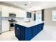 Modern kitchen features white cabinets, stainless appliances, and a blue island with a white countertop at 319 Ravenshill Way, Deland, FL 32724