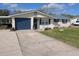 Single-story home with a blue metal roof and shutters, a spacious driveway and attached garage at 1628 Paradise Ln, Astor, FL 32102