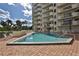 Community swimming pool surrounded by palm trees and lounge chairs at 3 Oceans West Blvd # 5C4, Daytona Beach Shores, FL 32118
