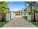 View of the long driveway leading up to the two-story home, framed by elegant gate posts at 3428 Longleaf Rd, Ormond Beach, FL 32174