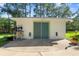 Exterior shot of a painted storage unit with a concrete pad, double doors, and yard tools at 3428 Longleaf Rd, Ormond Beach, FL 32174