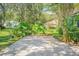 Landscaped backyard with lush greenery and a concrete driveway at 450 W Delaware Ave, Lake Helen, FL 32744