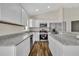 Bright kitchen featuring granite countertops, stainless steel appliances, and white cabinets with wood-look flooring at 210 E Baxter St, De Leon Springs, FL 32130
