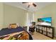 This bedroom has neutral toned walls, a ceiling fan, and features a comfortable chair and modern television at 309 Chesham St, Ormond Beach, FL 32174