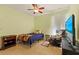 This bedroom features a ceiling fan, neutral-toned walls and a comfortable chair and modern television at 309 Chesham St, Ormond Beach, FL 32174