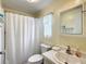 Well-lit bathroom features a shower with curtain, a toilet, and a sink with a mirror and vanity, offering convenience and functionality at 824 Silver Oak Ave, The Villages, FL 32159
