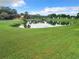 Beautiful pond surrounded by lush green grass and mature trees under a blue sky with white clouds at 824 Silver Oak Ave, The Villages, FL 32159