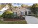 Tan one-story house with gray shutters, landscaping, and paved driveway at 210 Brookgreen Way, Deland, FL 32724