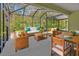 Relaxing screened patio featuring comfortable wicker furniture, a dining table, and views of the surrounding nature at 317 Nowell Loop, Deland, FL 32724