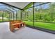 View of the screened-in porch with wood furnishings and a view of the green backyard at 317 Nowell Loop, Deland, FL 32724